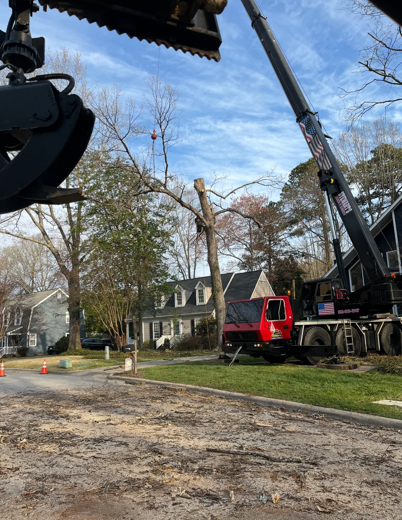 Fonvilletreeservice crane truck lifting large tree trunk section during residential tree removal operation in NC neighborhood