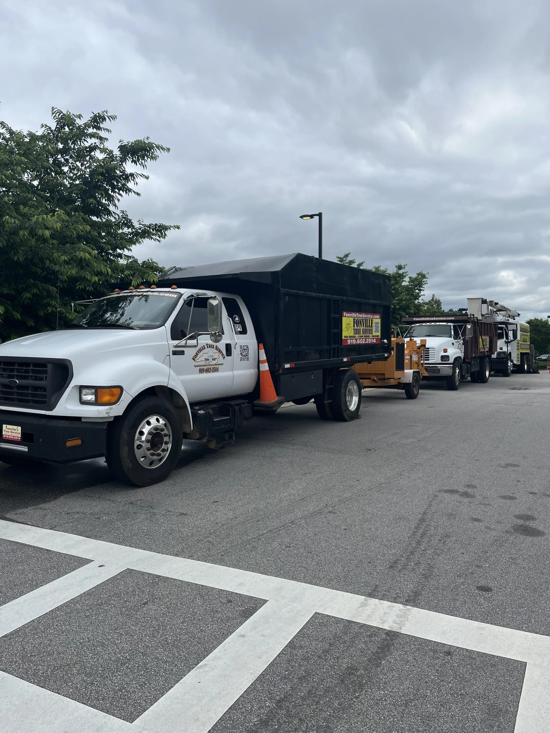 Fonvilletreeservice dump truck with debris bed and wood chipper trailer parked in commercial lot in NC ready for tree service work