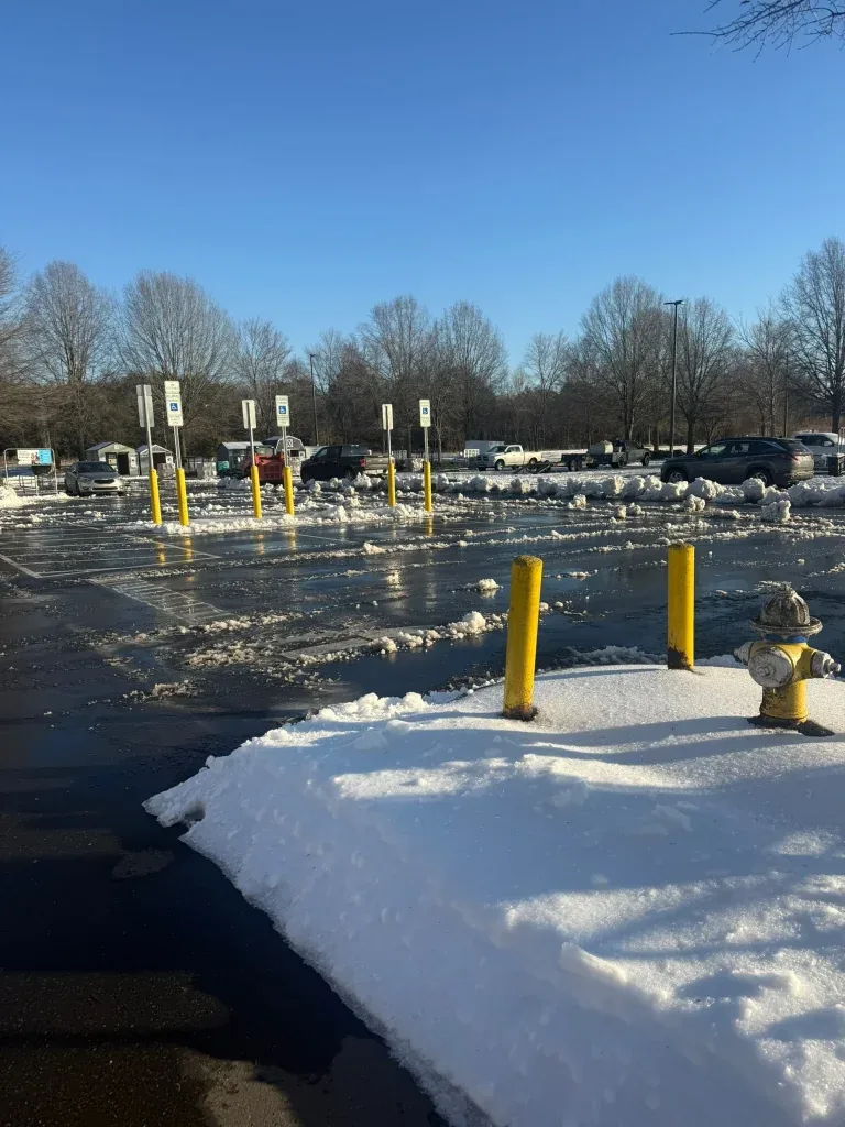 Fonvilletreeservice winter parking lot scene with snow piles yellow bollards and fire hydrant after clearing in NC