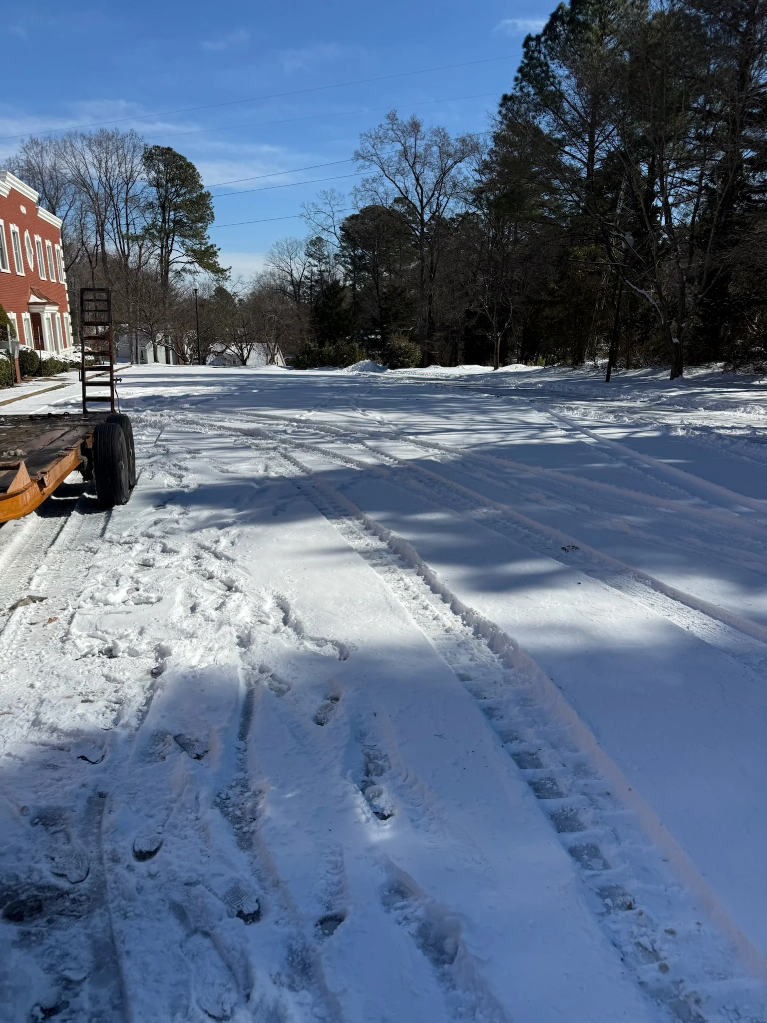 Fonvilletreeservice snow-covered commercial parking lot with tire tracks and footprints after winter storm in NC