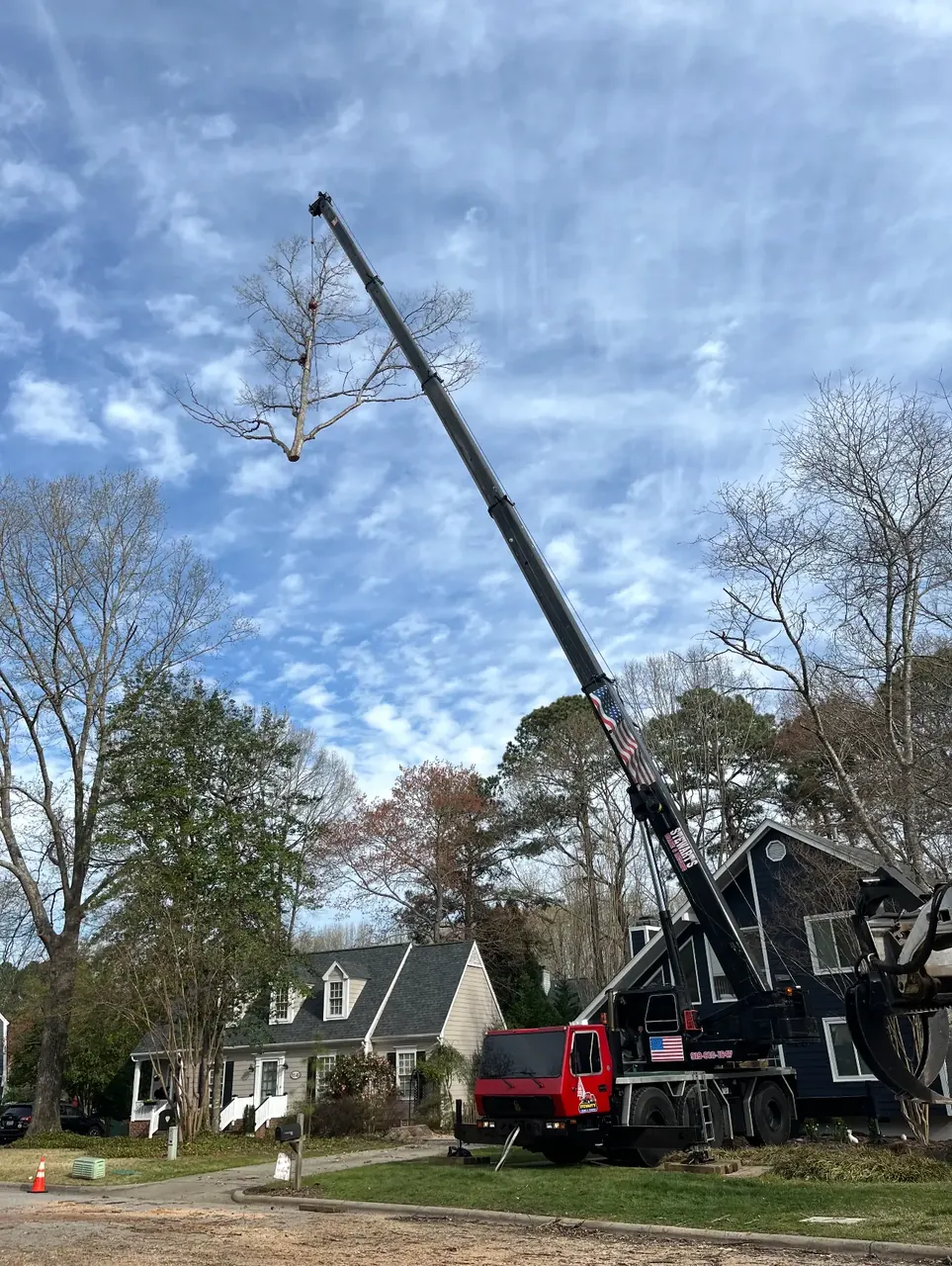 Crane extended over a home for a residential tree removal